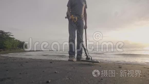 无法辨认的人带着电子金属探测器，带着他的狗在海洋热带沙滩上搜寻宝藏