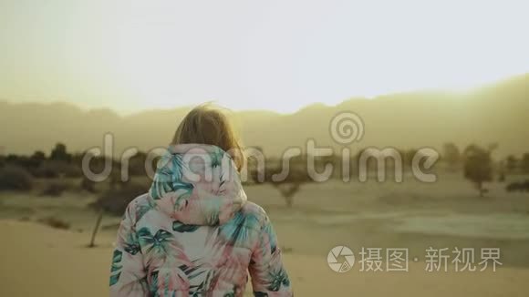 美丽的金发女人在沙漠中日落时散步。 女性穿越沙漠，沙丘，特写，慢动作，4k