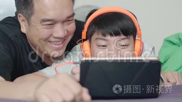 父亲和儿子在家里带着笑脸在平板电脑上欣赏电影