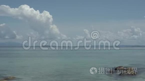 时光流逝，海滩上的水很少波浪和风，开放的天空有美丽的云。 泰国。