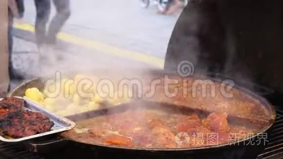 在户外咖啡馆的一个大圆锅上炸鲜肉和土豆。 在集市上招待饥饿的游客