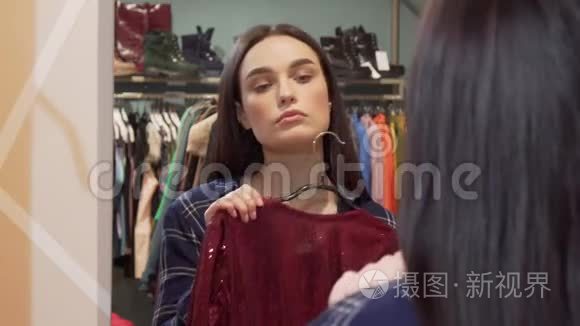 美丽的女人在两件衣服之间选择，在服装店购物