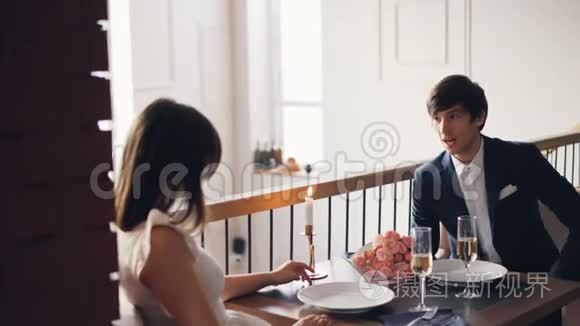 愤怒的年轻人正在和他沮丧的女朋友在漂亮的餐厅浪漫约会。 他在说话