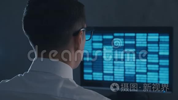 戴眼镜的专业IT极客程序员在夜间办公室用二进制代码工作