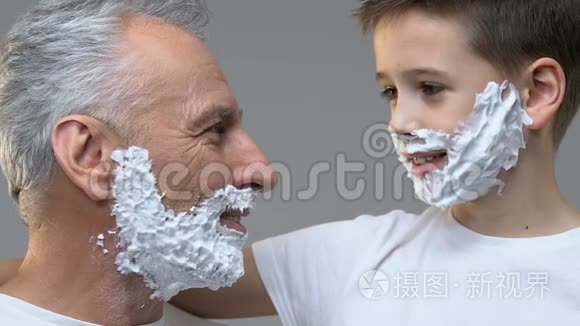 老人和孙子脸上有剃须泡沫，把剃须刀放在照相机里