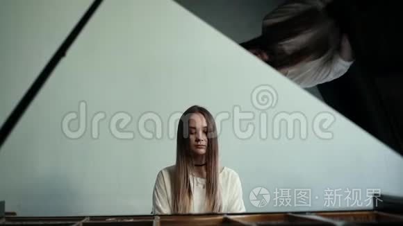 女钢琴家在墙上慢动作的背景下弹奏钢琴音乐