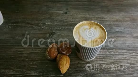 男人的手把第二个咖啡杯放在另一个和杏仁饼干旁边