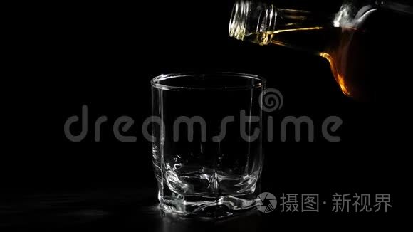 豪华威士忌。 手把金色的威士忌从一个方形的瓶子里倒入旋转的黑色桌子上的玻璃杯里。 不倒翁威士忌。 波旁