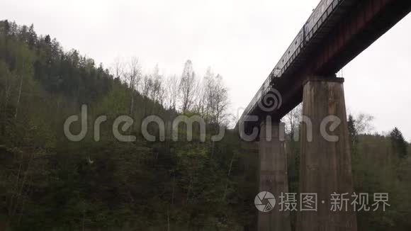 乘坐火车在一座古老的铁路桥上，在一个山村的底部