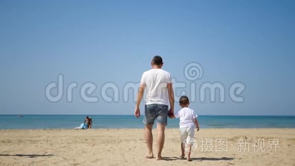 父子俩沿着海边沙滩朝大海走去视频