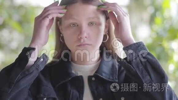 悲伤的少女在镜头中靠近她的头发的肖像。 年轻女子的手指穿过头发