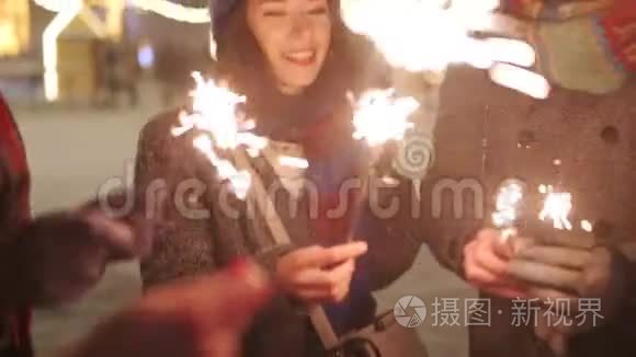 朋友们手里拿着火花挥舞。 女孩在圣诞前夜、新年假期或生日聚会上尽情欢乐