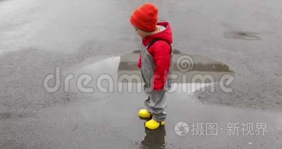 穿黄靴子的男孩穿过水坑视频