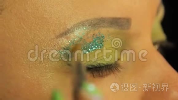 一个拿着刷子的女人眼睛上布满了绿色的阴影，多汁的绿色火花