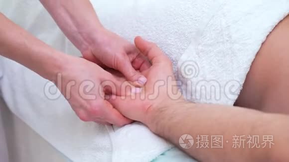 女性手在治疗室为男性病人做手掌放松按摩