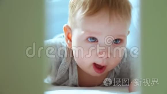 一个小孩在婴儿床上的特写镜头，笑着试图爬行。 快乐的童年，幼稚的快乐，进入的第一步