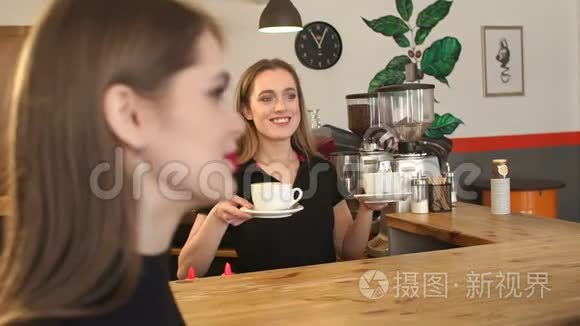 微笑的咖啡师女孩在咖啡店里为一对年轻夫妇提供一杯咖啡。