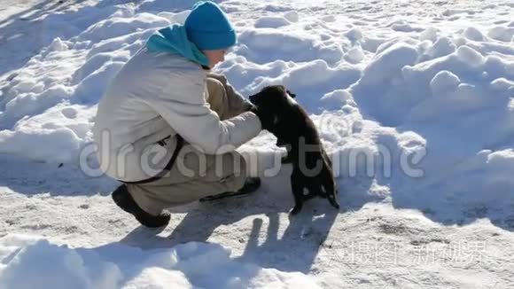 男孩少年在冬天的雪地里玩小狗。