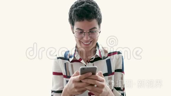 微笑的年轻商务女性使用她的手机，而站在白色的背景。