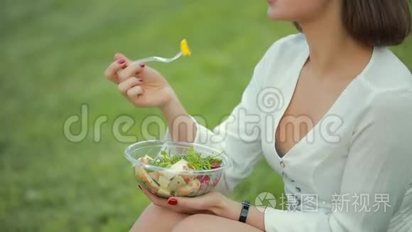 坐在草地上吃沙拉的美女