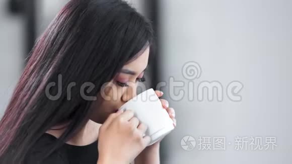 迷人的亚洲年轻微笑女孩双手捧着大白杯，享受热饮料