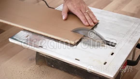 圆锯上的切割层压板地板，手握面板的细节