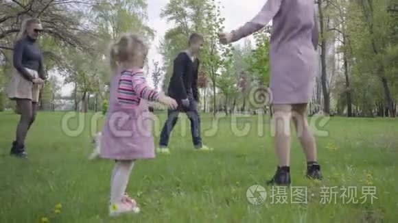 两个可爱的妈妈在春天的时候和他们的孩子在绿色神奇的公园里玩。 妈妈和儿子，女儿在玩