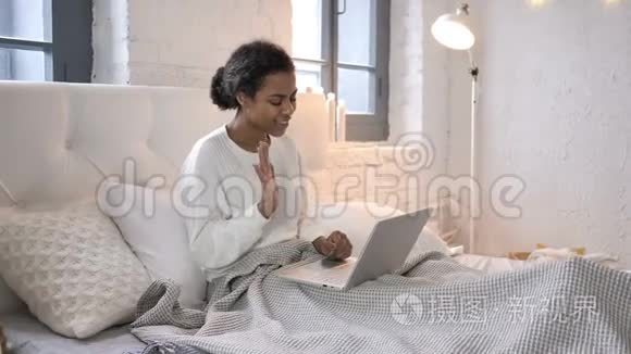 坐在床上的非洲少女在笔记本电脑上的在线视频聊天