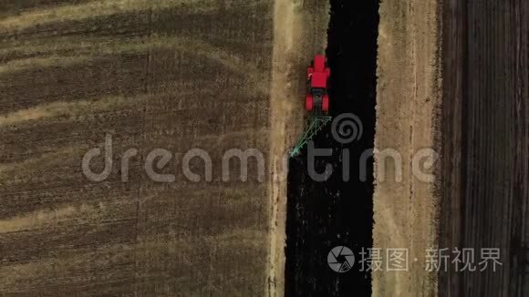 俯视图红色拖拉机耕田，准备播种土地.. 空中观景。 农民在拖拉机上准备土地