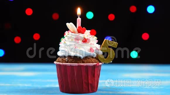 带有蜡烛的美味生日蛋糕和五色迷离灯光背景上的5号蛋糕