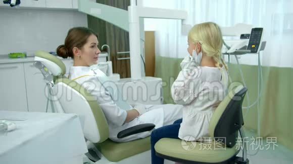 牙医坐在病人的椅子上和女孩说话