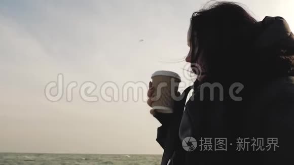 女孩在海天相接的背景下，用一次性杯子喝一杯