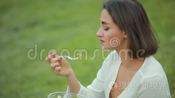 坐在草地上吃沙拉的美女