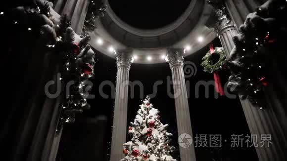 在神圣的夜晚，用柱子覆盖着雪装饰在凉亭里的圣诞树。