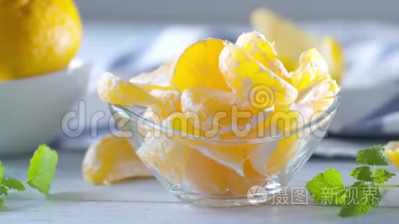 新鲜成熟的橘子和香草梅丽莎在玻璃碗在木桌上。 视频镜头4K50fps