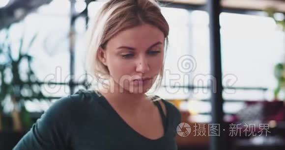 一个金发女人早上在家里客厅做瑜伽练习的肖像，她伸展身体以获得