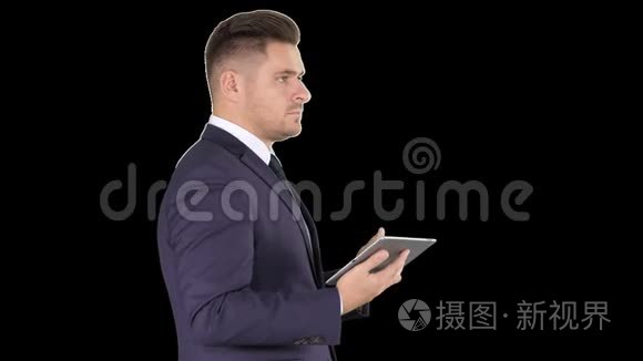 年轻的商人触摸数码平板电脑，在他面前检查物品，阿尔法频道