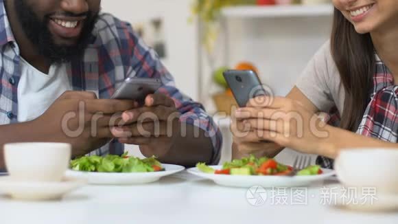 多种族夫妇在晚餐时使用智能手机，缺乏真正的沟通
