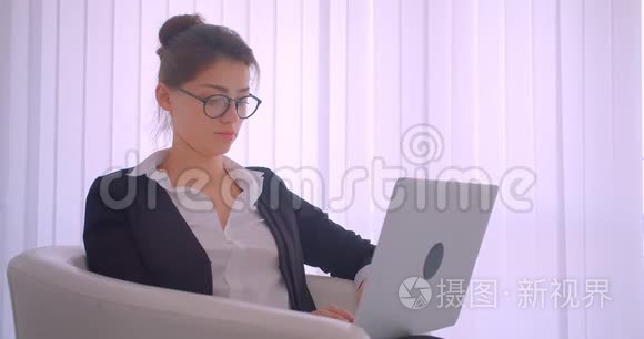 一位年轻漂亮的高加索女商人在一间白色房间里用笔记本电脑拍摄特写镜头