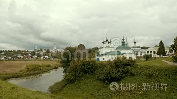 村庄景观-一条小溪，教堂和鸟儿在天空中飞翔-苏兹达尔，俄罗斯