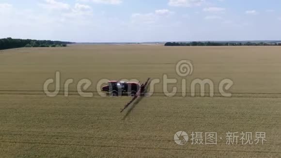 一个自动推进喷雾机的长臂将小麦喷洒在一大片田野上