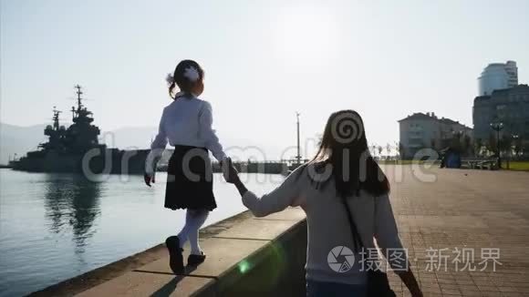 一个穿校服的女孩正和妈妈一起走在长廊的栏杆上。