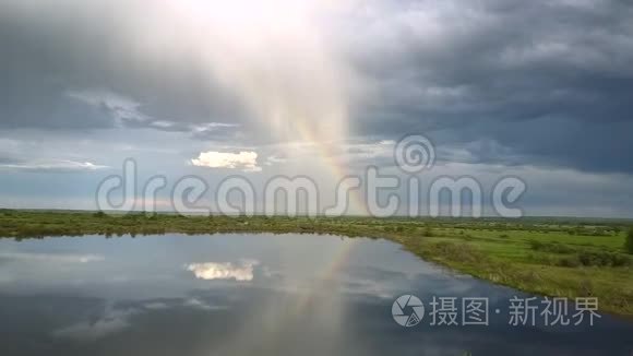 在平静的湖泊和草地上，巨大的彩虹和浓密的云