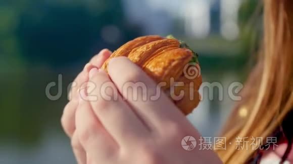 女孩的特写`双手捧着一个新鲜的羊角面包,动作缓慢. 新鲜的甜点.