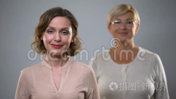 美丽的女性在镜头前微笑，年长的女士在背后，安全和健康的衰老