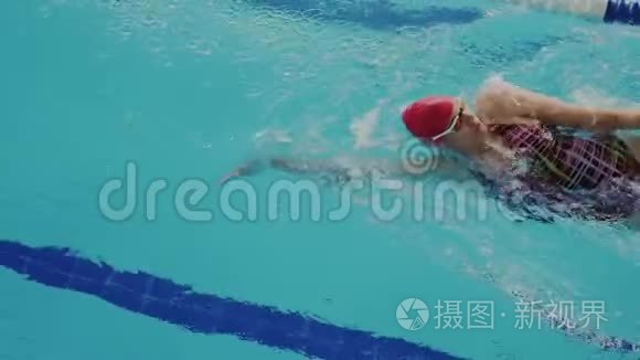 业余女游泳运动员在泳池泳道游泳时的俯视图。 她放松，使她的身体