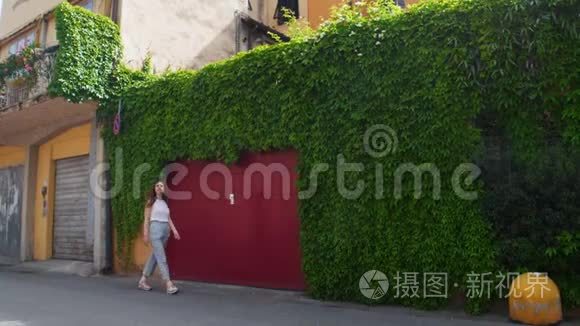 年轻女子穿过街道穿过绿墙视频