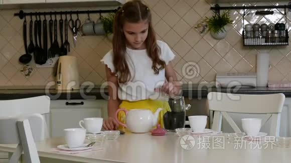 一个女孩从厨房的桌子上清洗一罐茶