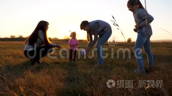 快乐的孩子和妈妈和姐妹一起玩球。 一家人在日落时分`公园里玩小孩的球