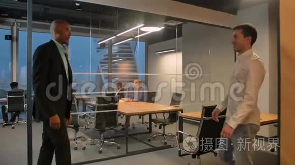 两位企业家在现代办公室的室内握手。 美洲人和高加索人的同事。